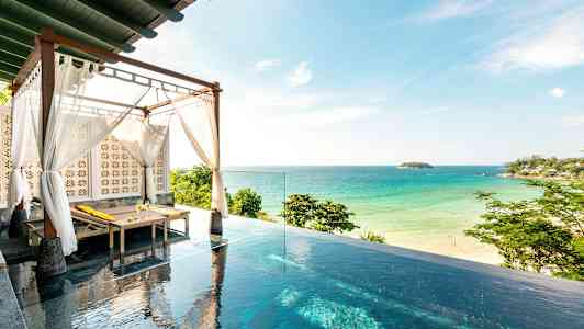 Kuvassa on infinity-allas, jossa on aurinkotuoli katoksen alla valkoisilla kankailla, ja taustalla näkyvät hiekkaranta ja meri. (Tekoälyn luoma teksti)