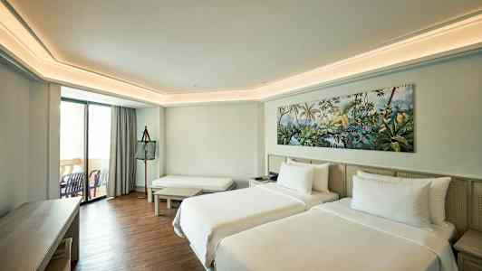 Hotellihuone, jossa on kaksi yhden hengen vuodetta, istuinalue ja parveke. (Tekoälyn luoma teksti)