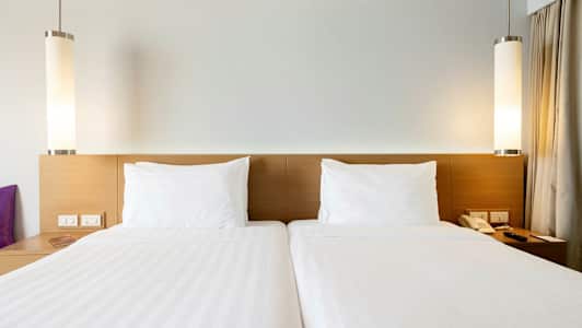 Kaksi yhden hengen sänkyä valkoisilla lakanoilla ja tyynyillä. (Tekoälyn luoma teksti)