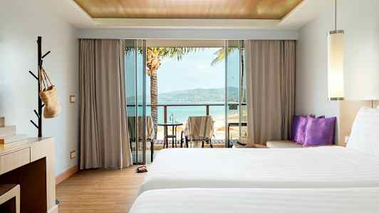 Hotellihuone, jossa kaksi sänkyä, työpöytä ja parveke, josta näköala rannalle. (Tekoälyn luoma teksti)