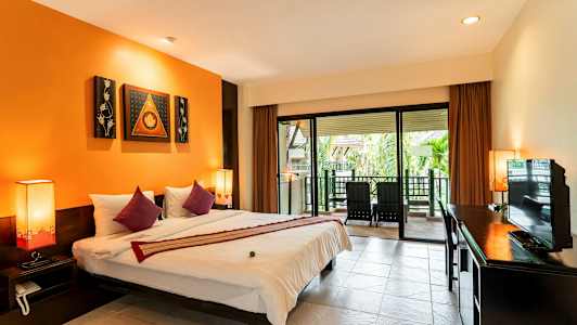 Hotellihuone, jossa suuri sänky, oranssit seinät ja terassi ulkopuolella, jossa tuoleja. (Tekoälyn luoma teksti)