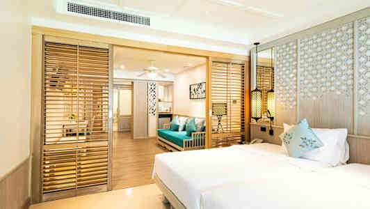 Hotellihuone, jossa parivuode, sininen sohva ja puurakenteita. (Tekoälyn luoma teksti)