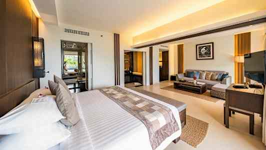 Valoisa hotellihuone, jossa parivuode ja oleskelutila. (Tekoälyn luoma teksti)