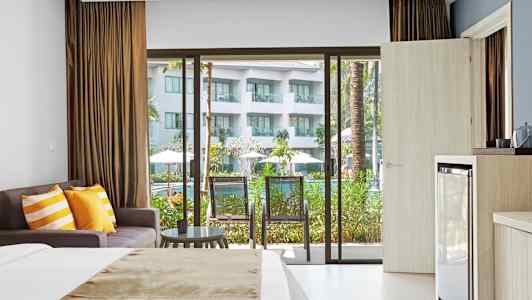 Hotellihuone, jossa sänky, sohva ja parveke näkymällä uima-allasalueelle. (Tekoälyn luoma teksti)