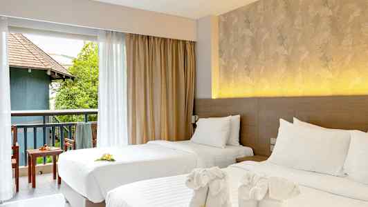 Kaksi pedattua yhden hengen sänkyä koristeellisilla pyyhkeillä ja kukilla. Näkymä kalustetulle parvekkeelle, jossa vihreää ja rakennus. (Tekoälyn luoma teksti)