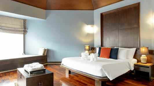 Hotellihuone, jossa on parivuode, eri värisiä tyynyjä sängyllä ja pyyhkeistä tehtyjä koristeita eläimen muotoisina. (Tekoälyn luoma teksti)