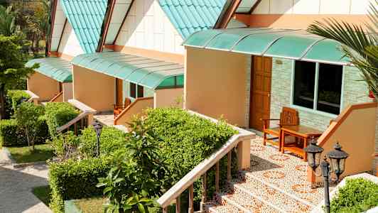 Rivi pieniä taloja, joissa vihreät katot ja portaat kasvien ympäröimänä. (Tekoälyn luoma teksti)