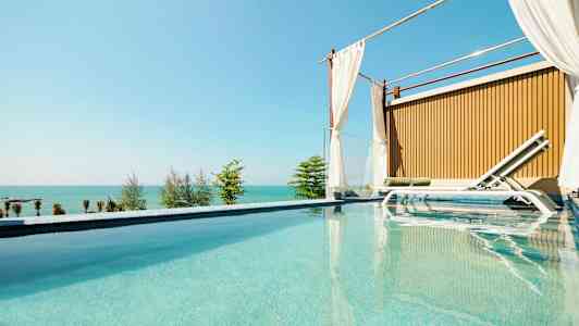 Ylellinen uima-allas, jonka vieressä on aurinkotuoli ja taustalla merinäköala. (Tekoälyn luoma teksti)