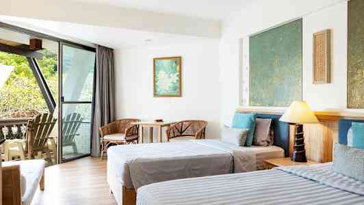 Hotellihuone, jossa kaksi sänkyä, istuinryhmä ja parveke näköalalla. (Tekoälyn luoma teksti)