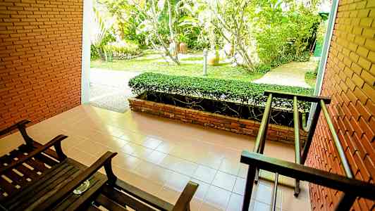 Terassi, jossa on kaksi tummaa puutuolia ja näkymä puutarhaan. (Tekoälyn luoma teksti)