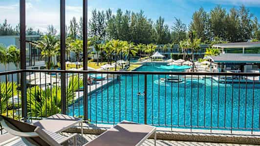 Uima-allas, jota ympäröivät rakennukset ja palmut, nähtynä verannalta, jossa on aurinkotuoleja. (Tekoälyn luoma teksti)