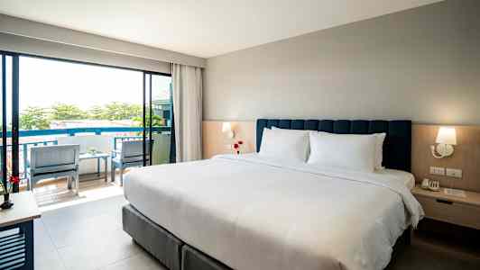 Hotellihuone, jossa on parivuode, yöpöytä ja näkymä parvekkeelle. (Tekoälyn luoma teksti)