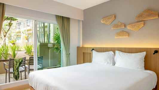 Hotellihuone kuva, jossa kaksoisvuode, lähellä lasiovea, josta pääsee ulkoterassille, jolla on istuimia. (Tekoälyn luoma teksti)