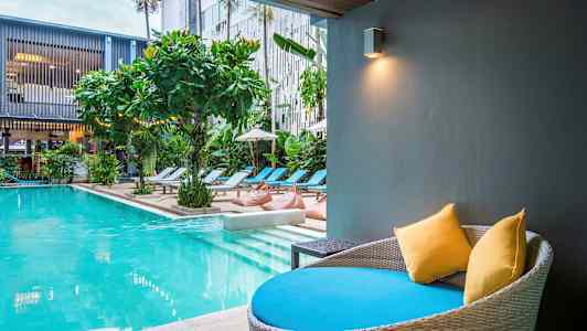 Moderni uima-allas aurinkotuoleilla ja kasveilla. Etualalla istumapaikka tyynyineen. (Tekoälyn luoma teksti)