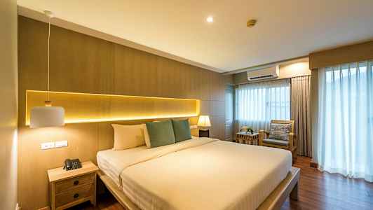 Makuuhuone, jossa suuri sänky, sivupöytä ja verhot ikkunassa. (Tekoälyn luoma teksti)