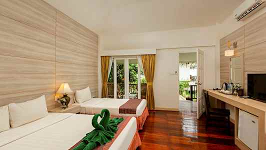 Hotellihuone, jossa on kaksi sänkyä, ovi, joka johtaa puutarhaan, pöytä tuoleineen sekä lamppuja ja koristeita. (Tekoälyn luoma teksti)