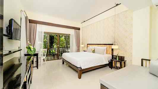 Huone, jossa on parivuode, sänky nurkassa ja seinällä televisio, sekä parveke, jolta on näkymät vehreyteen. (Tekoälyn luoma teksti)