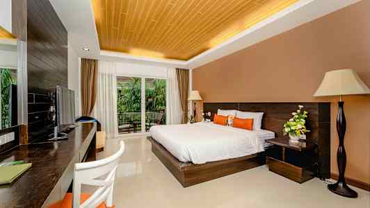 Hotellihuone, jossa on parivuode, kirjoituspöytä, televisio ja suuret lasiovet, joista on näkymä parvekkeelle ja vehreään ympäristöön. (Tekoälyn luoma teksti)