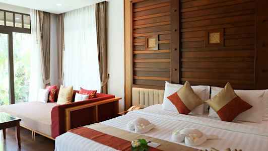 Makuuhuone, jossa on iso sänky koristeltu tyynyillä ja pyyhescgureilla sekä sohva suuren ikkunan vieressä. (Tekoälyn luoma teksti)