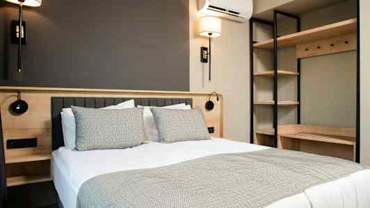 Moderni makuuhuone, jossa on parivuode, sängynvalaisimia ja hyllytilaa. (Tekoälyn luoma teksti)