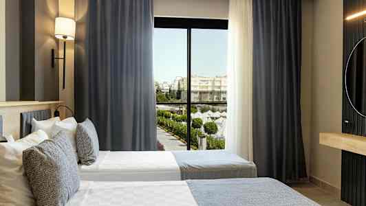 Hotellihuone, jossa kaksi yhden hengen vuodetta ja ikkuna, josta näkyy uima-allasalue. (Tekoälyn luoma teksti)