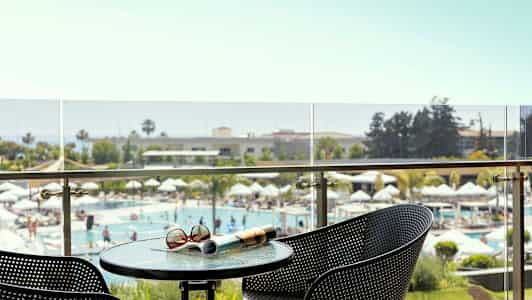 Näköala parvekkeelta uima-allasalueelle, jossa on aurinkovarjoja ja vehreää ympäristöä. (Tekoälyn luoma teksti)