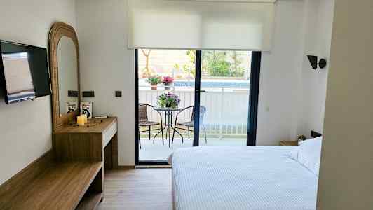 Hotellihuone, jossa on parivuode, kirjoituspöytä, televisio ja parveke puutarhakalusteilla. (Tekoälyn luoma teksti)