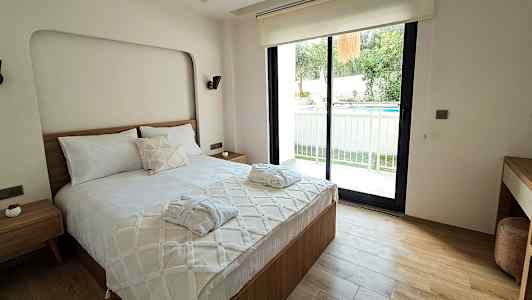 Makuuhuone, jossa on parisänky, ikkuna avautuu ulkoterassille ja uima-altaalle. (Tekoälyn luoma teksti)