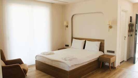 Hotellihuone, jossa on parivuode, nojatuoli ja yöpöytä. (Tekoälyn luoma teksti)