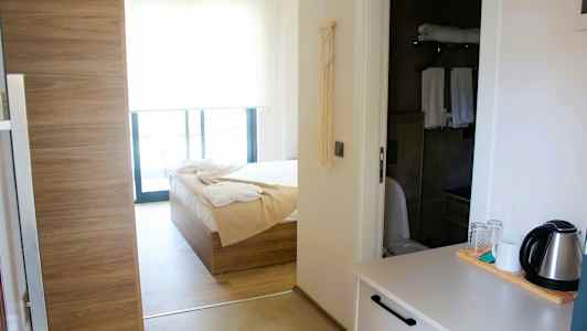 Hotellihuoneen sisustus, jossa on sänky, kylpyhuone ja vedenkeitin tasolla. (Tekoälyn luoma teksti)