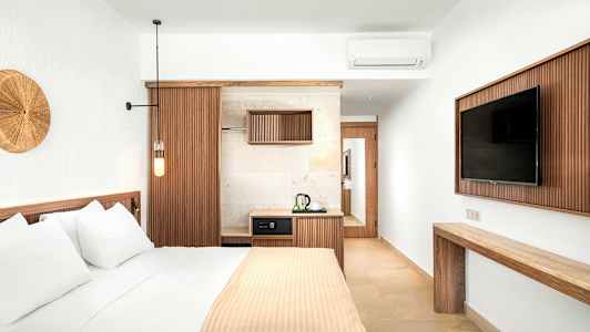 Tyylikäs hotellihuone, jossa vuode, televisio ja pieni keittonurkkaus. (Tekoälyn luoma teksti)