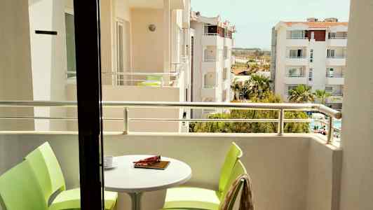 Kuva parvekkeelta, jossa pöytä ja tuolit sekä näkymä ympäröiviin rakennuksiin. (Tekoälyn luoma teksti)