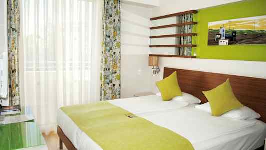 Hotellihuone, jossa on parisänky ja vihreät vuodevaatteet. (Tekoälyn luoma teksti)