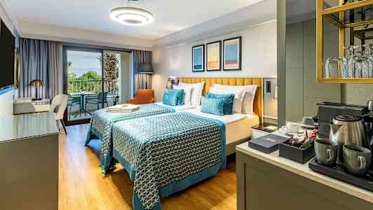 Hotellihuone, jossa kaksi erillistä vuodetta, parveke ja kahvikeittiö. (Tekoälyn luoma teksti)