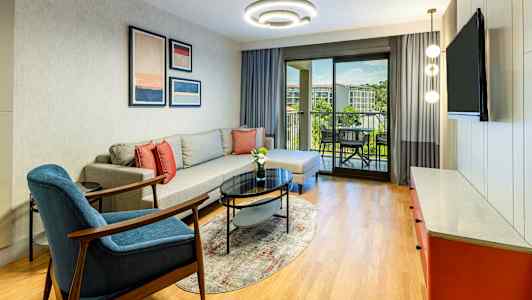 Olohuone, jossa sohva, nojatuoli, sohvapöytä ja näkymä parvekkeelle. (Tekoälyn luoma teksti)