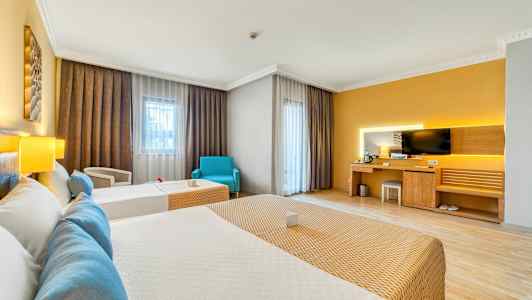 Hotellihuone, jossa kaksi vuodetta, työpöytä nurkkaus television kanssa ja suuret ikkunat verhoilla. (Tekoälyn luoma teksti)