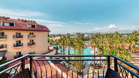 Näkymä parvekkeelta hotellirakennukseen, uima-altaalle ja palmupuille. (Tekoälyn luoma teksti)