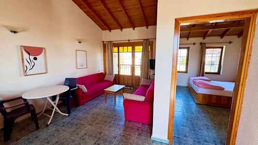 Olohuone, jossa on punaiset sohvat ja puuhuonekalut, sekä viereinen makuuhuone. (Tekoälyn luoma teksti)