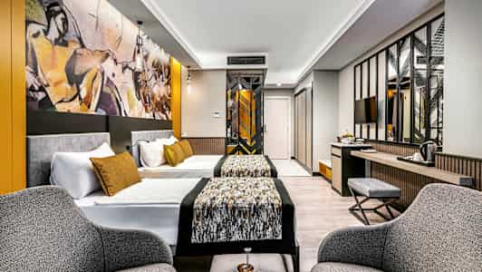 Moderni hotellihuone, jossa kaksi vuodetta, istuinryhmä ja taidetta seinällä. (Tekoälyn luoma teksti)