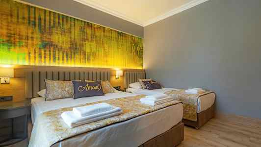 Kaksi sänkyä hotellihuoneessa, jossa on harmaat seinät ja keltainen sisustus. (Tekoälyn luoma teksti)