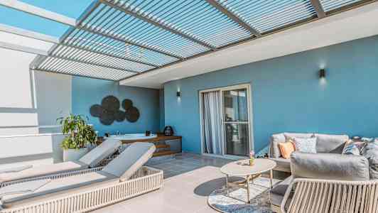 Terassi, jossa aurinkotuoleja, sohva ja pöytä pergolan alla. (Tekoälyn luoma teksti)