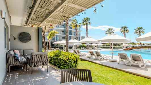 Ulkoterassi, jossa istuimia, ja näkymä uima-altaalle, jossa on aurinkotuoleja ja päivänvarjoja. (Tekoälyn luoma teksti)