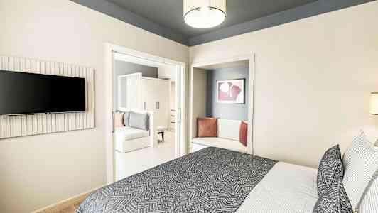 Moderni hotellihuone, jossa sänky, tekstiilit ja istuinalue. (Tekoälyn luoma teksti)