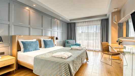 Hotellihuone, jossa kaksisänky, kaksi nojatuolia ja työpöytä. (Tekoälyn luoma teksti)