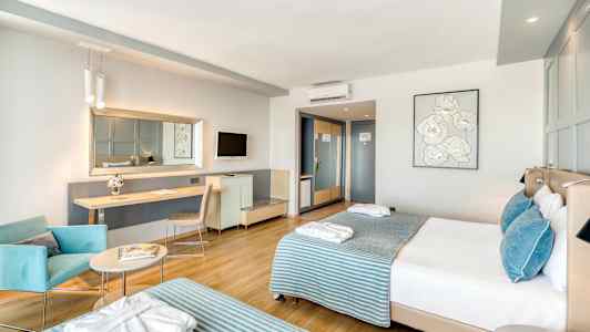 Moderni hotellihuone, jossa on kaksi vuodetta, istuinalue ja työpöytä. (Tekoälyn luoma teksti)