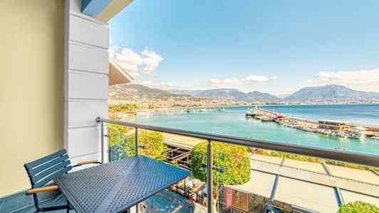 Parveke, jolta on näkymä satamaan ja kaukaisiin vuoriin. (Tekoälyn luoma teksti)