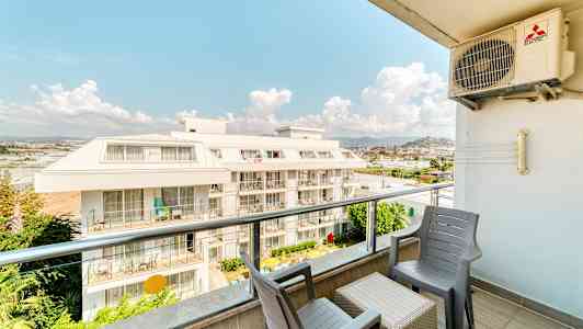 Näkymä parvekkeelta, jossa on tuoleja ja pöytä, näkymä kerrostaloon. (Tekoälyn luoma teksti)