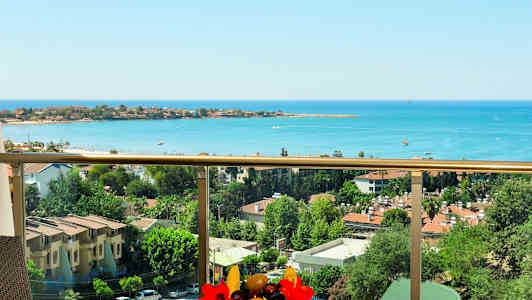 Näköala parvekkeelta merelle ja rakennuksiin, jotka ympäröivät puita. (Tekoälyn luoma teksti)