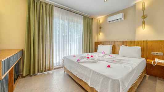 Hotellihuone, jossa on parivuode pedattu valkoisilla lakanoilla ja koristeltu kukilla. (Tekoälyn luoma teksti)