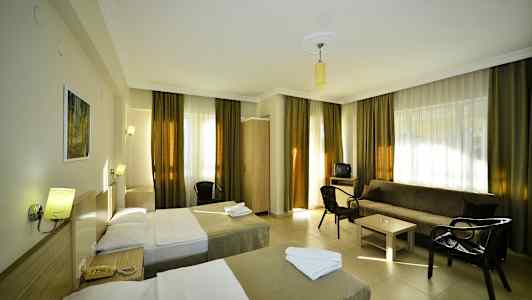 Hotellihuone, jossa kaksi yhden hengen vuodetta, sohva, pöytä ja tuolit. (Tekoälyn luoma teksti)